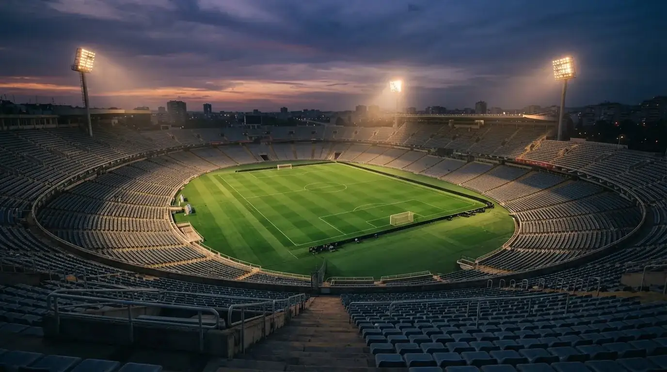 An empty football stadium with floodlight masts at dusk