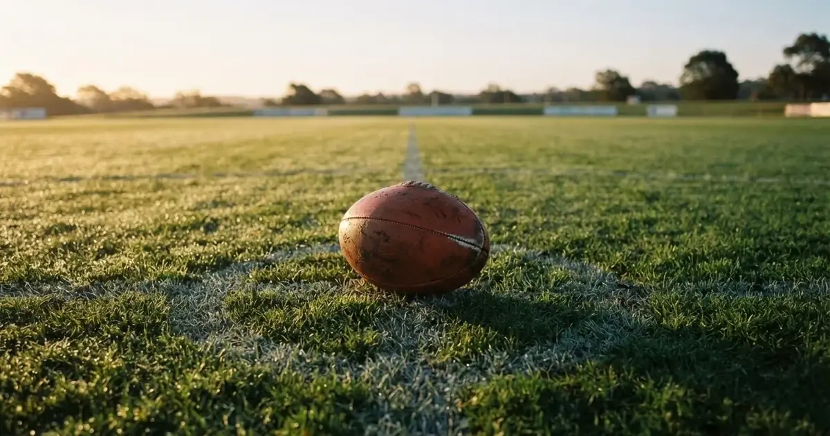 A ball on the centre spot of a grass pitch in morning light