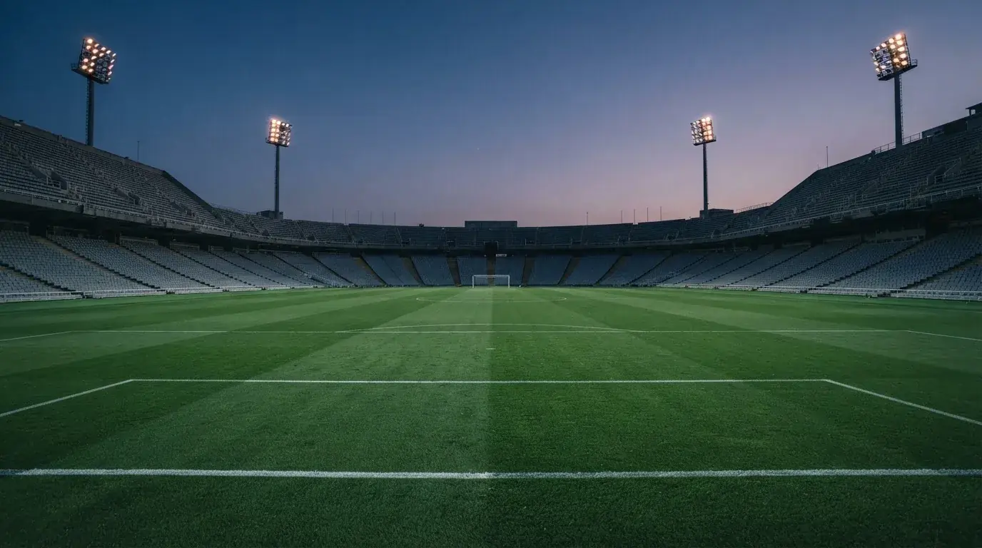 An empty football stadium with floodlight masts at dusk