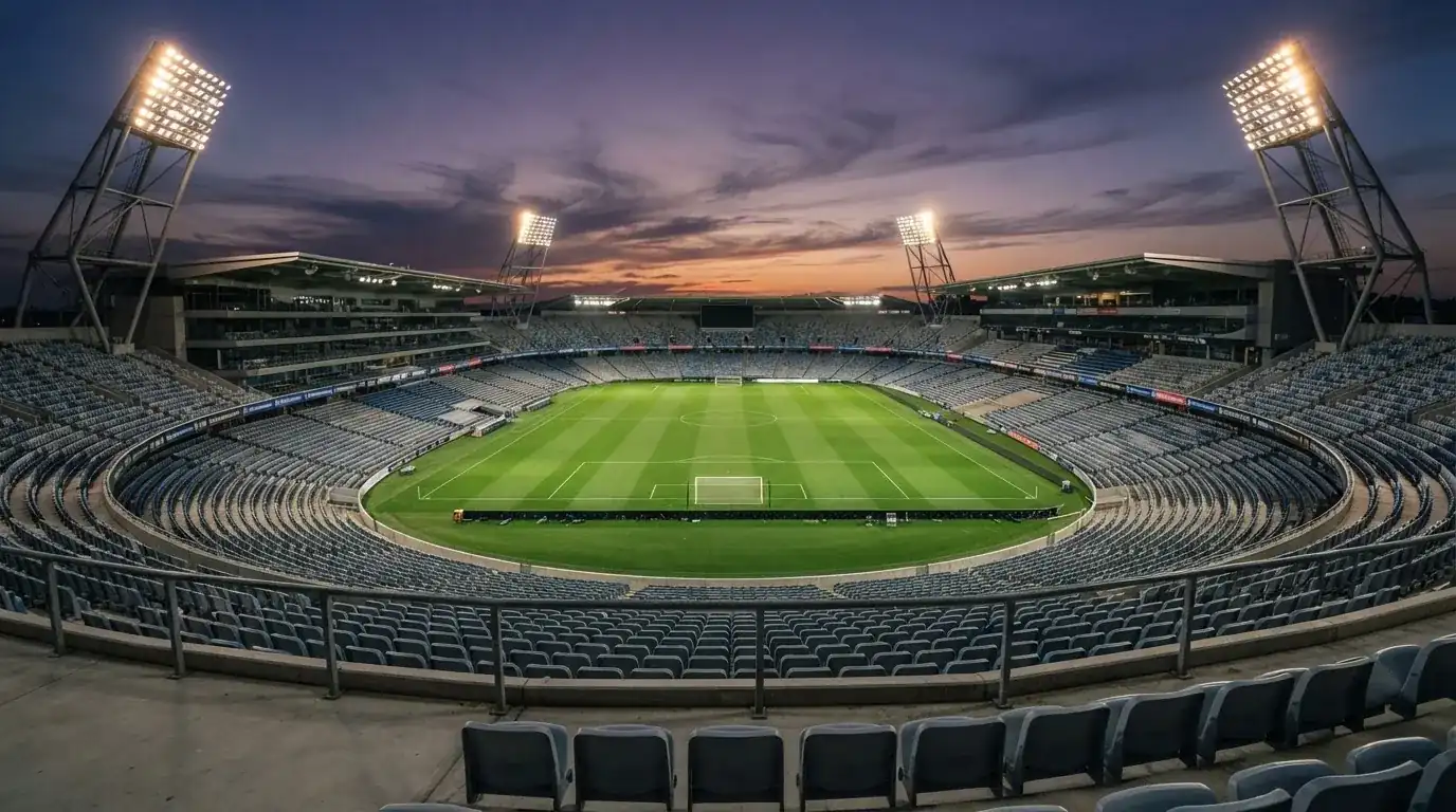 An empty football stadium with floodlight masts at dusk