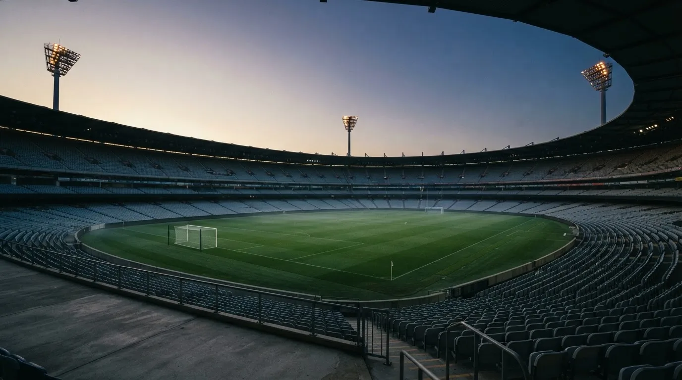 An empty football stadium with floodlight masts at dusk