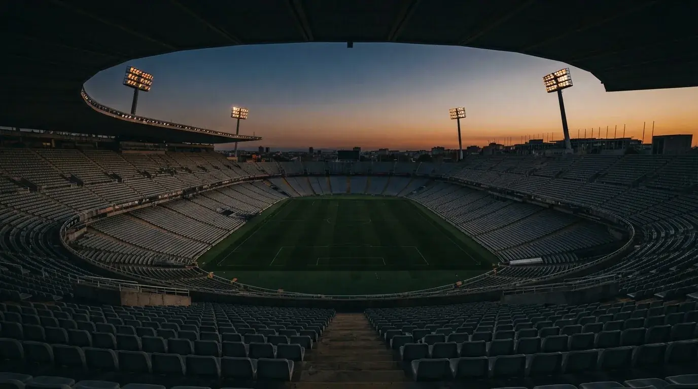 An empty football stadium with floodlight masts at dusk