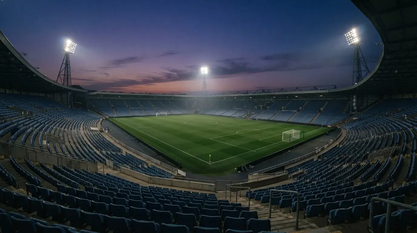 An empty football stadium with floodlight masts at dusk