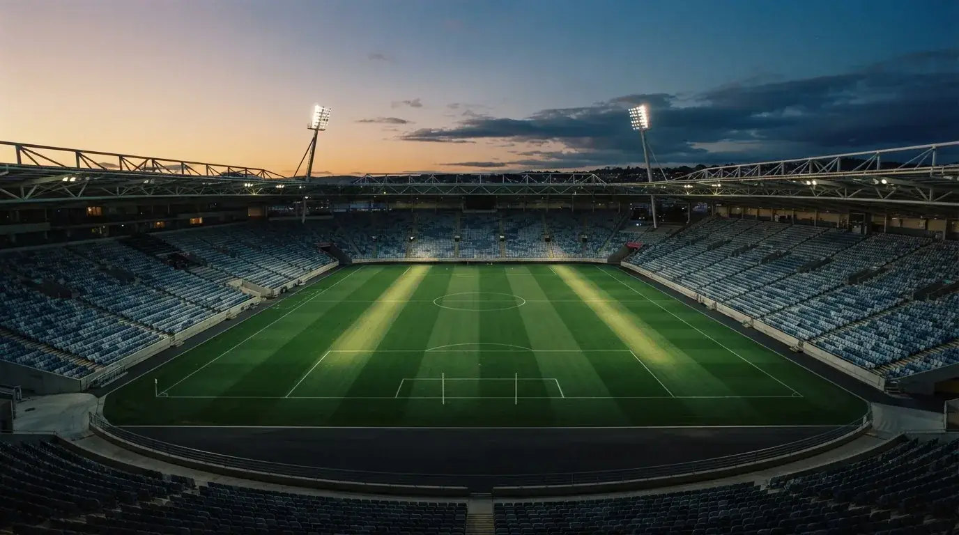 An empty football stadium with floodlight masts at dusk