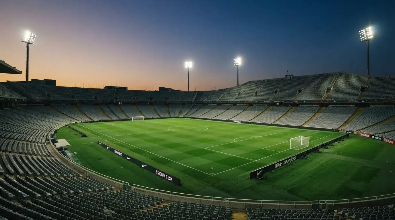 An empty football stadium with floodlight masts at dusk