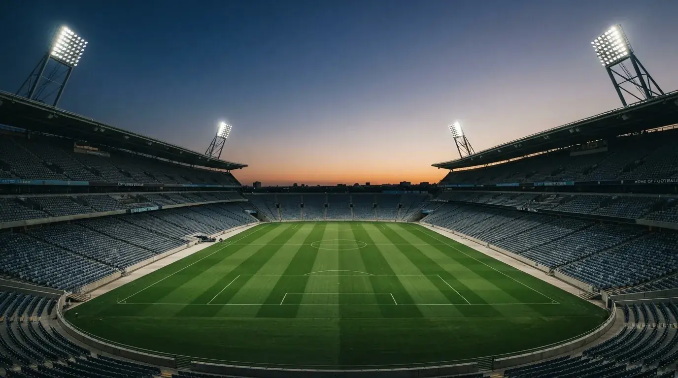 An empty football stadium with floodlight masts at dusk