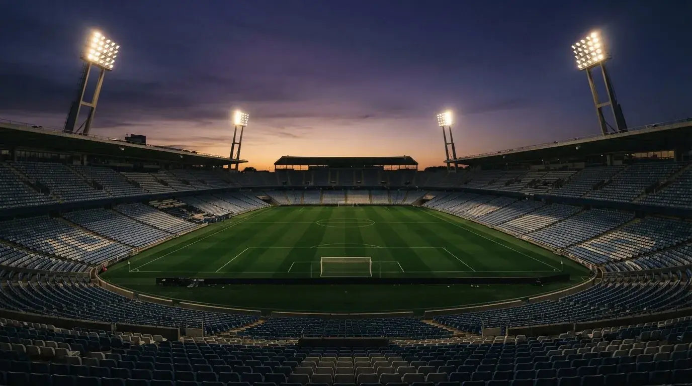 An empty football stadium with floodlight masts at dusk