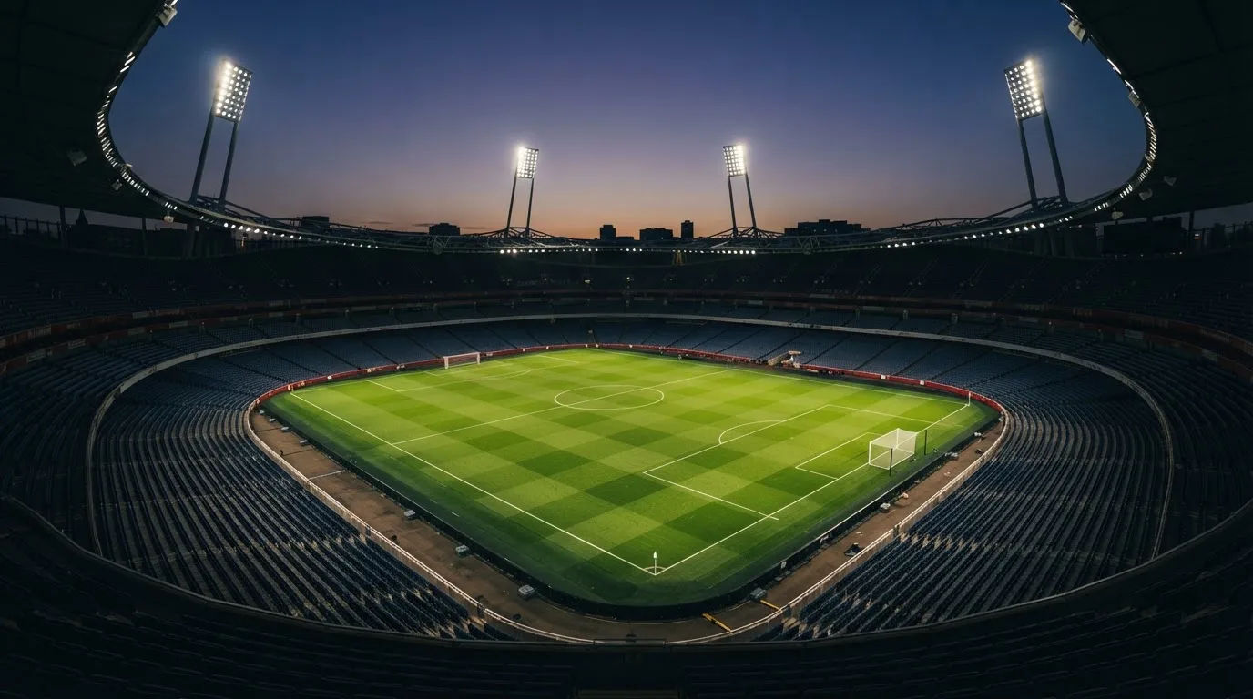 An empty football stadium with floodlight masts at dusk