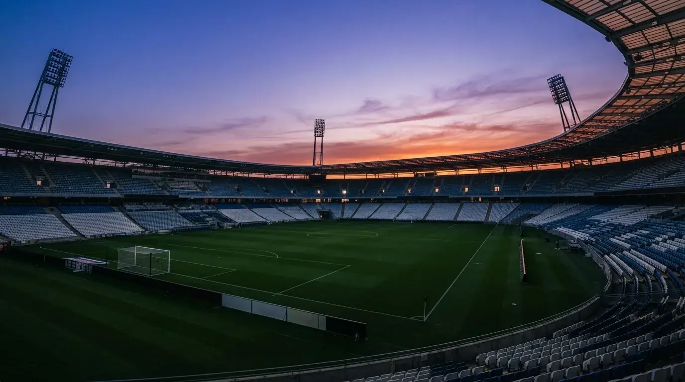 An empty football stadium with floodlight masts at dusk
