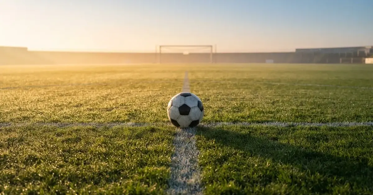 A ball on the centre spot of a grass pitch in morning light