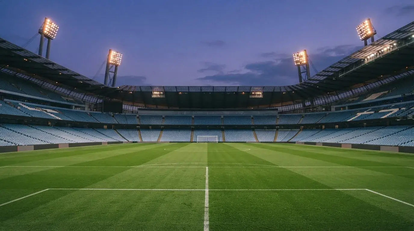An empty football stadium with floodlight masts at dusk