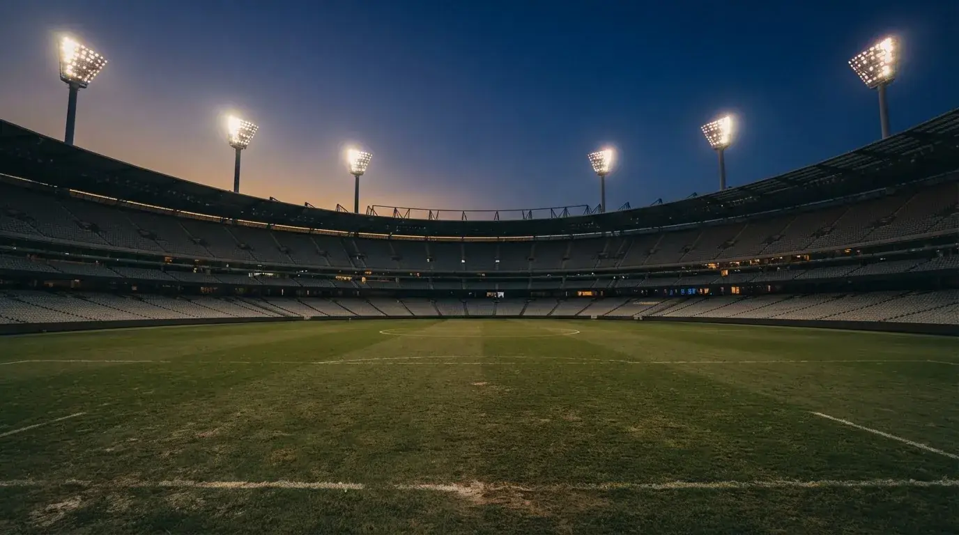 An empty football stadium with floodlight masts at dusk