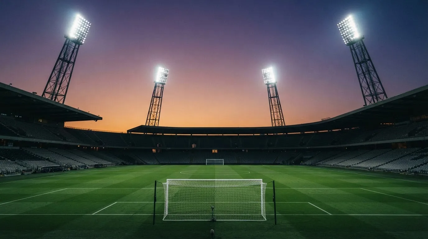 An empty football stadium with floodlight masts at dusk