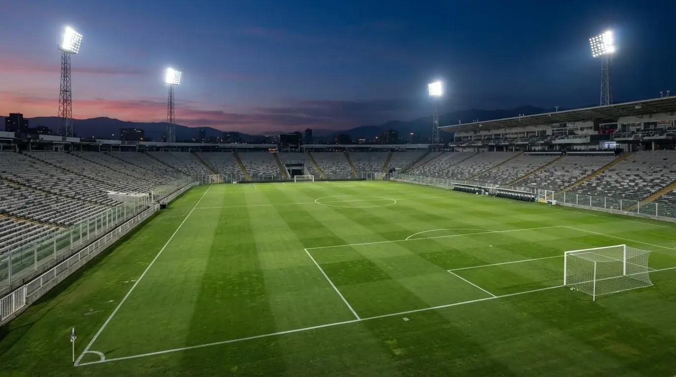 An empty football stadium with floodlight masts at dusk