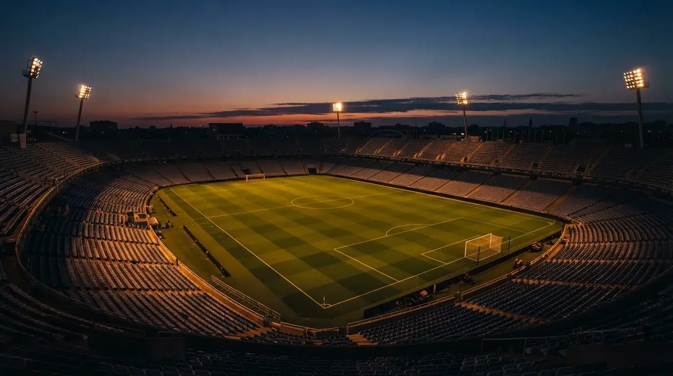 An empty football stadium with floodlight masts at dusk