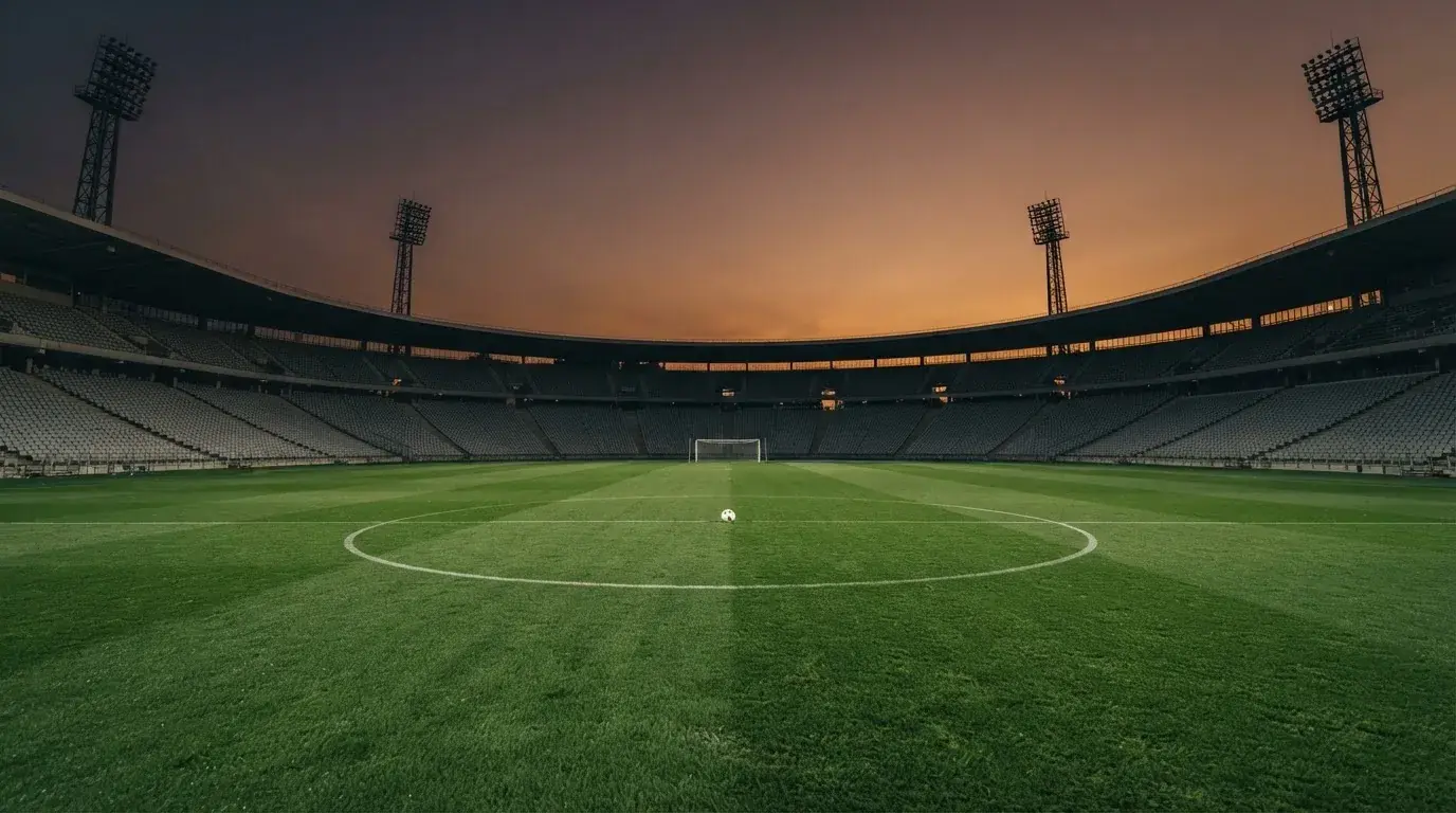 An empty football stadium with floodlight masts at dusk