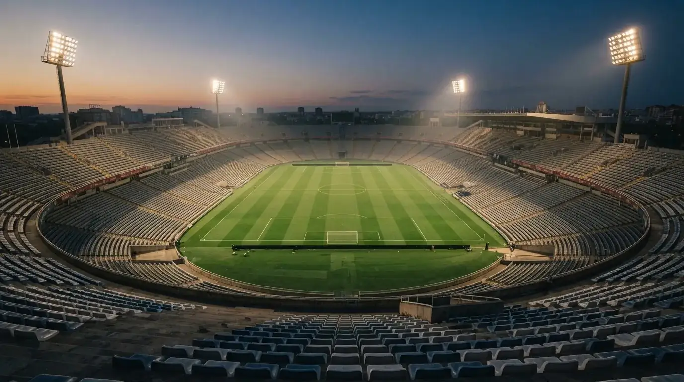 An empty football stadium with floodlight masts at dusk